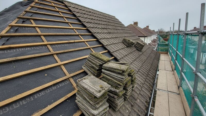 Full re-roof with old tiles stripped exposing battens on a UK house